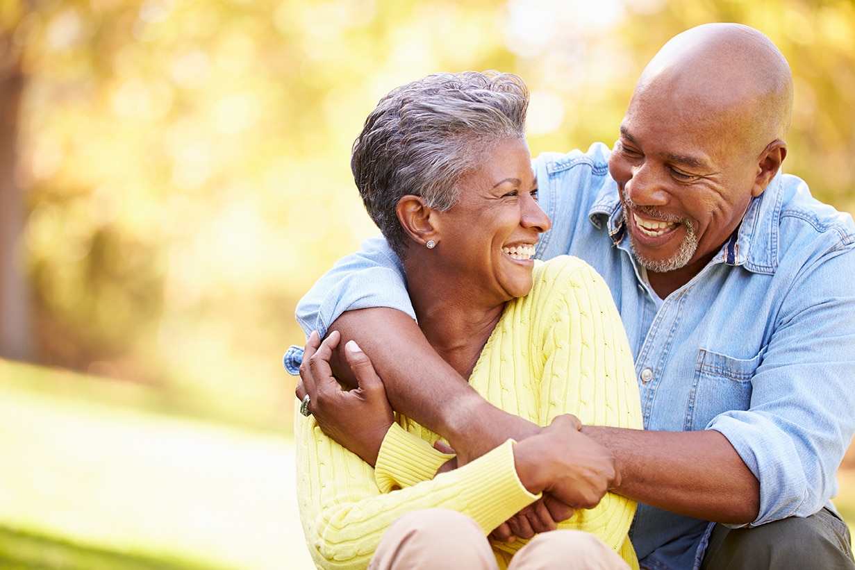 woman smiling with husband hugging her in a park in aurora colorado